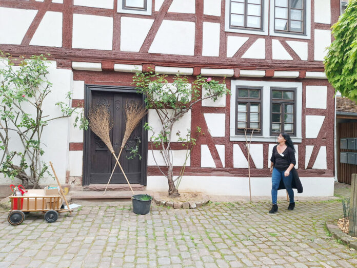 Anke vor Haus mit Besen Bollerwagen