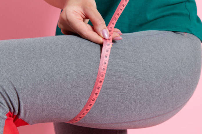 front-view-young-female-green-t-shirt-measuring-her-sizes-pink-wall-waist-sport-exercise-workout-beauty-slim-athlete