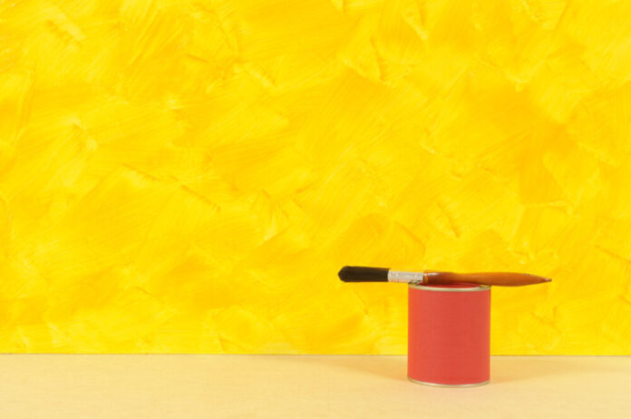 Painted yellow wall with red paint tin