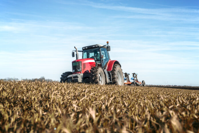 Tractor agricultural machine cultivating field.